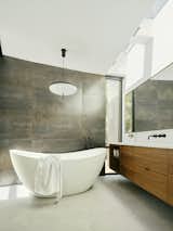 The luminous primary bathroom features an Aquatica Purescape 171 Freestanding Tub, along with matte black faucets from Crosswater London. The pendant above the tub is a Gino Sarfatti Model No. 2065 Ceiling Light.