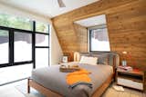 The cozy guest bedroom receives ample light from the rear facade’s floor to ceiling glazing, along with the “eyeball” dormer to the north.  Photo 7 of 8 in A Sleek A-Frame Rises From the Ashes in Lake Tahoe, California