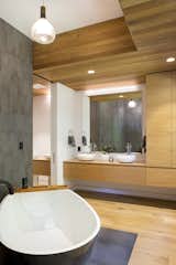 One of the home’s six bathrooms, the spa-like space favors natural materials like textural wood and stone.