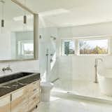 The home’s primary bathroom includes a wood vanity, a soaking tub, and operable windows overlooking southeastern vistas.
