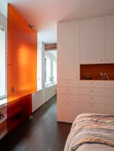 An orange resin door playfully pivots open and closed to partially separate the sleeping area from the rest of the apartment.