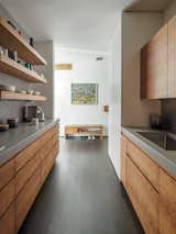 The home’s galley kitchen features cherry cabinetry and a concrete counter and backsplash—tying in with the concrete wall in the living room.