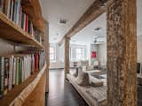 Original to the 1918 building, the wood columns and beams retain remnants of paint from years past. Opposite the columns, the live edge library wall is made from a single log, cut down the middle, and sliced into thick shelves.