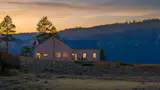 In low light conditions, the home's metal roof reads darker and more saturated in color, blending in with the shadows of the mountainside beyond.