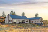 In bright daylight conditions, the home’s standing seam metal roof appears visually light—complementing the tones of the charred wood cladding. A metal retaining wall is an extension of the home’s metal siding, wrapping in a ribbon-like fashion around the lower perimeter.