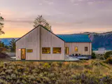 The home’s two pitched volumes—one containing the great room and primary suite, and the other housing guest quarters and a kids’ bedroom—converge in a nearly-perpendicular configuration.
