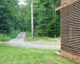 The home is accessed via a long gravel drive through the woods