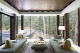 The living room is wrapped in glass on three sides, also offering direction connection to the new pool deck and a view to the small stream below.