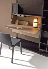 The La Literatura modular shelving unit can feature a push-latch panel that opens to reveal a work surface and office storage. 