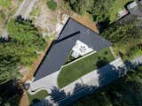 An overhead drone shot of the house, which borders a railroad track but offers small groves of trees at its edges.