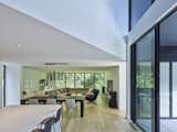 The high-ceilinged kitchen and dining area give way to a more intimate living area that focuses on the wide-screen view through the glass to the trees.