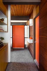 All the doors have been painted burnt orange—a tribute to Christopher’s grandmother—and match the pads on the homeowners’ seats at the kitchen table. The pebble-inflected concrete floor is original.