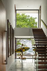 Homeowner and co-designer Christopher Hansen heads for the beach from the home’s double-height entry hallway, where a glass stairway with parota wood treads maintains sight lines.