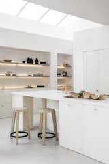 The kitchen is bathed with natural light thanks to a skylight above, and the kitchen island rests on blocks of coarse, pitted travertine.