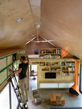 A double-height great room offers extra storage accessed by a vintage library ladder, and a pair of loft rooms underneath the pitch of the exposed, plywood-covered vaulted ceiling.
