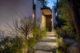 The home keeps a low profile as it greets the street, but its entry path is lined with lush plant life.