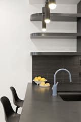 The kitchen is finished with matte-black surfaces and a curve motif, with pops of color from its sink hardware.