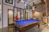 A concrete platform in the main living area features a pool table near a reclaimed, stained-glass sliding door.