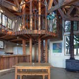 A spiral staircase, welded balustrade, and exposed wood beams create a loftlike aesthetic in the double-height space.