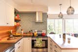 The couple removed a portion of the kitchen cabinetry in favor of open shelving, which helps highlight the wall of Heath Ceramics tile behind the stove.