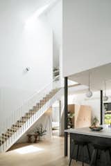 The foyer gives way to a dramatically long, uninterrupted staircase, with the living room and kitchen at right.