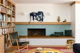 The new den's rebuilt fireplace is clad with the same Heath Ceramics tile as the kitchen island. Avove it is a Christopher Wrobleski rope hanging. A vintage Hans Wegner chair with Maharam leather cushions was paired with a Lawson Fenning San Rafael Paolo coffee table.