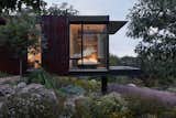 At one end of the house is the primary bedroom, which enjoys floor-to-ceiling glass views and its own porch.