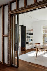 The design team stripped drywall from a wall in the hallway and left the wood framing exposed on one side. It now holds a metal and glass pocket door to the office. The shelves are by&nbsp;Vitsoe Shelving, and the silk and wool rug is by Coe &amp; Son.