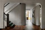The renovated stairway now has a rounded wall at its base, to pair with the curved wall across from it and make room for more natural light from the extension's glass wall to spread into the interior.