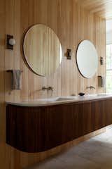 The primary bathroom features floating walnut cabinetry set against Accoya walls.