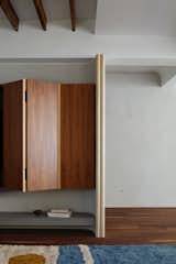 In the living room, a curved partition wall wraps the walnut media cabinet.