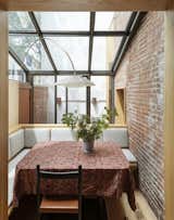 In the sun room dining extension, the exposed brick that was formerly on the exterior was left in place. The light fixture is custom. The Marianne Tablecloth is by Autumn Sonata and the Juniper Chair is by Sun at Six.