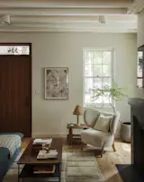 The renovated living room features new pine flooring, inspired by the home's original flooring. The Izra Rug is by General Assembly for Salam Hello, the Assembly Occasional Table is by General Assembly, and The TMBO Lounge Chair is from Mazo, all available at Assembly Line.