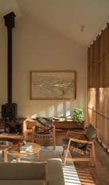 In the living room, a wood stove keeps temperatures cozy. The artwork (of the ill-fated St. Francis Dam and reservoir) is by Al Stone, as is the built-in stove platform and bench seat. The sofa is from Blu Dot, the vintage Risom Lounge Chairs from Knoll and pillows by Kiriko Made.