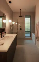 In the primary bathroom, the floor and wall tile is Quartziti Glacier by Satements. The Bola Sphere Suspension Lamp is by Pablo Designs.