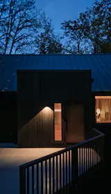 The entry, seen here at night, pops out from the pitched-roof house to provide a larger foyer.