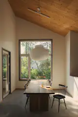 The dining table sits beside a door to the outdoor deck, making it easy to entertain with combined indoor-outdoor presence. The Strand pendant light is by Muuto.