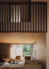 The living room sits beneath the mezzanine-like upstairs bedrooms, with a knotty fir ceiling providing a touch of rustic cabin vibes. The Chill Time sofa is by Sundays.