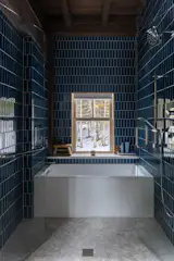 The bathroom includes a Carrera marble mosaic hex floor, and Hammer Topaz wall tile by Wow, as well as a tub by Kohler with a Moen faucet — all installed by Scott's son, Gabriel Schultz.
