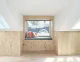 In the primary bedroom, the dormer window seat's The S&amp;B Colour Pillows are from Hay.