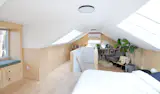 After adding insulation and a mini-split, the primary bedroom is also a comfortable place to hang out. Light from the skylights reflect off the white wall and ceilinb surfaces.