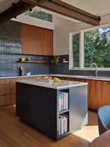 With the peninsula counter and upper cabinetry removed, the kitchen is open to the adjacent dining area, while the kitchen island adds cook space.