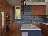 The redesigned kitchen maintained plenty of cupboard space by taking better advantage of the left wall for storage, including, near the window, a cupboard from which the hidden TV unfolds.