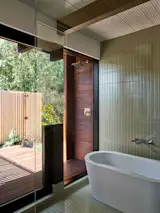 The new primary bathroom, clad in Fireclay Terre Verte wall and floor tiles, took advantage of its increased square footage to add a freestanding tub. It gives way to a new enclosed deck and outdoor shower.