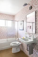 A bathroom for kids features retro-style materials, including a vintage-inspired sink, toilet, and pink mosaic tile.