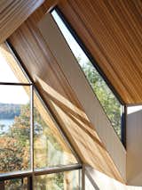 Geometric windows allow for curated views of the surrounding landscape and invite natural light to flood the interior, reflecting off the sharp roof angles and creating dramatic lines and shadows.
