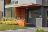 The front façade of the house features a fresh approach to traditional design elements; the home’s entrance is accessed on the side of the foyer volume instead of from the front. A complementary Corten steel planter defines the granite porch and serves as a designated area for displaying the house number.
