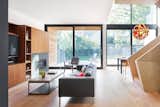 Large windows connecting the interior spaces to the outdoors blur the boundaries between inside and outside. Within the living room, the use of walnut millwork and a slate fireplace surround offers a striking contrast to the light-colored white oak flooring and stair.