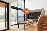 The dining room sits within a double-height atrium with a fully-glazed rear facade that provides an expansive view of the neighbourhood’s mature trees, inviting natural light deep into the interior and magnifying the grandeur of this modest space.