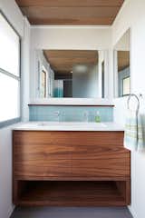 Klopf Architecture and Jesse Ososki Art remodeled an existing Eichler atrium home into a brighter, more open, and more functional version of its original self. 

The goals were to preserve the Eichler look and feel without the need to strictly adhere to it. The scope of work included re-configuring the master bedroom/bath, the kitchen, and the hall bath/laundry area, as well as updating interior finishes throughout to be more sophisticated.

The owners are detail-oriented and were very involved in the design process, down to the selection of lighting controls and stainless steel faceplates.Their design aesthetic leans toward the Scandinavian — light and bright, with simple straight lines and pure geometric shapes.

The finish flooring is large porcelain tile (24” x 24”) in a neutral grey tone, providing a uniform backdrop against which other materials can stand out. The same tile continues into the shower floor (with a different finish texture for slip-resistance) and up the shower/tub walls (in a smaller size). Heath Classic Field ceramic tile in Modern Blue was used sparingly, to add color at the hall bath vanity backsplash and at the shampoo niches in both bathrooms. Back-painted soda glass in pale blue to match the Heath tile was used at the kitchen backsplash. This same accent color was also used at the front entry atrium door. Kitchen cabinetry, countertops, appliances, and light fixtures are all white, making the kitchen feel more airy and light. Countertops are Caesarstone Blizzard.

The owners chose to keep some of the original Eichler elements:  the concrete masonry fireplace; the stained tongue-and-groove redwood ceiling decking; and the luan wall paneling. The luan paneling was lightly sanded, cleaned, and re-stained. The owners also kept an added element that was installed by a previous owner: sliding shoji panels at all bedroom windows and sliding glass doors, for both privacy and sun control. Grooves were cut into the new tile flooring for the shoji panels to slide in, creating a more integrated look. Walnut was used to add warmth and contrast at the kitchen bar top and niche, the bathroom vanities, and the window sill/ledge under the kitchen window.

This Burlingame Eichler Remodel is a 2,121 sf, 4 bedroom/2 bath home located in the heart of Silicon Valley.

Klopf Architecture Project Team: John Klopf, Klara Kevane and Yegvenia Torres Zavala
Contractor: Jesse Ososki Art 
Structural Engineer: Emmanuel Pun
Photography ©2018 Mariko Reed
Location: Burlingame, CA
Year completed: 2017



